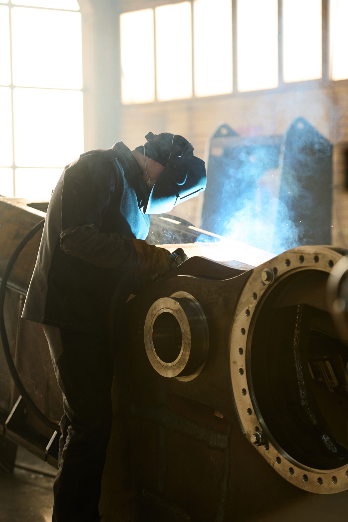 Side view of engineer in protective mask during process of arc welding